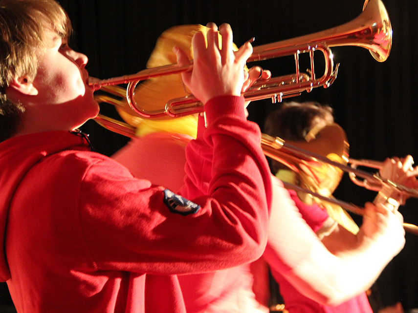 Barn i röda tröjor spelar på trumpet