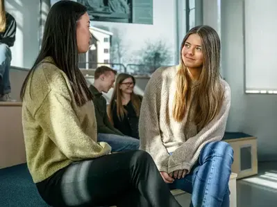 två kvinnliga elever diskuterar på rasten.