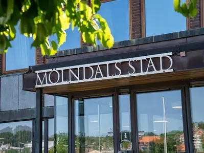 Mölndals stads logga på stadshuset med blad i förgrunden