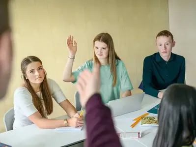 En elev räcker upp handen för att svara på en fråga under en lektion.