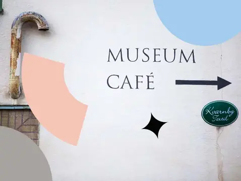 foto på en vit vägg där det står museum och café samt en pil.